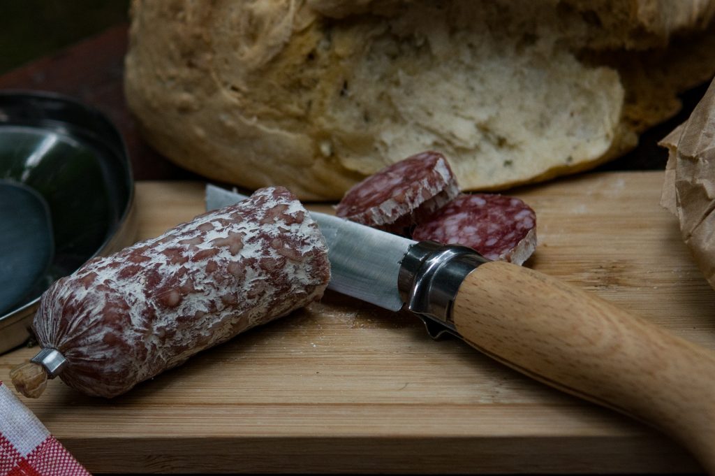 Opinel knife cutting sausage